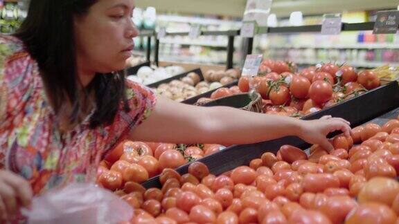 亚洲女人的手在超市挑选橘子