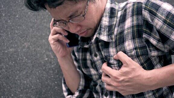 4K视频:心脏病发作一个男人抓着自己的胸部同时使用电话拨打紧急电话