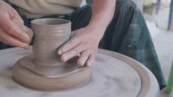 这张照片拍摄的是一名女陶工用陶工转轮上的一团粘土塑造陶罐