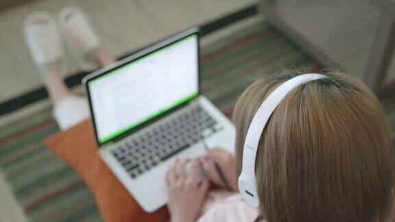 俯视图场景的年轻亚洲妇女通过电子学习自己在家里使用笔记本电脑