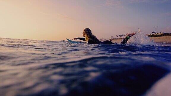 在日落时分冲浪女孩在冲浪板上跑进加利福尼亚的海洋