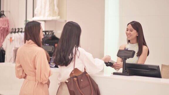 亚洲华人精品店女店主互动与她的客户收银员与信用卡购买结账
