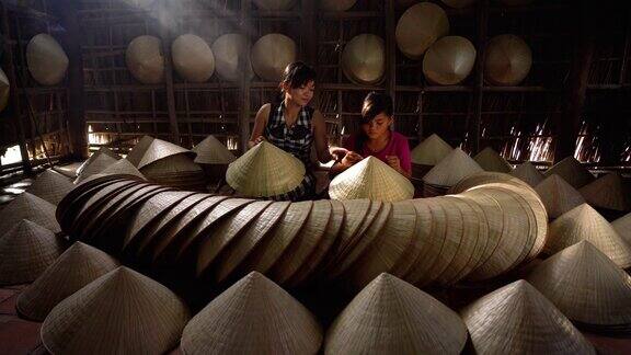 在越南Cantho省的ApThoiPhuoc村的老传统房子里4k镜头的越南工匠教女孩制作传统的越南帽子传统艺术家