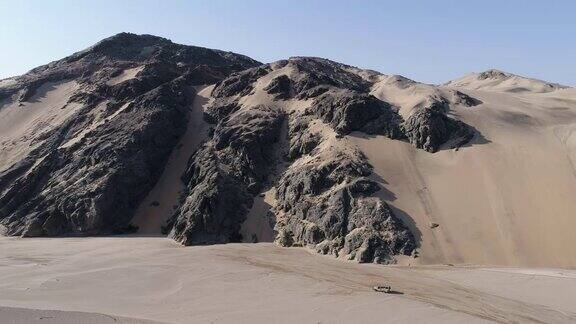 4K空中缩小视野的safari汽车驾驶旁边的沙丘带游客观光古老的地质岩层在纳米比亚沙漠纳米比亚