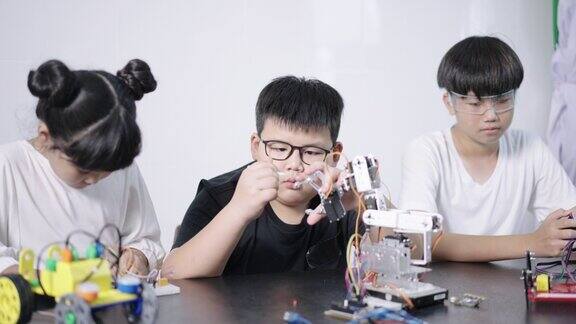 一群男孩和女孩建立和学习机器人STEM编程软件和修复