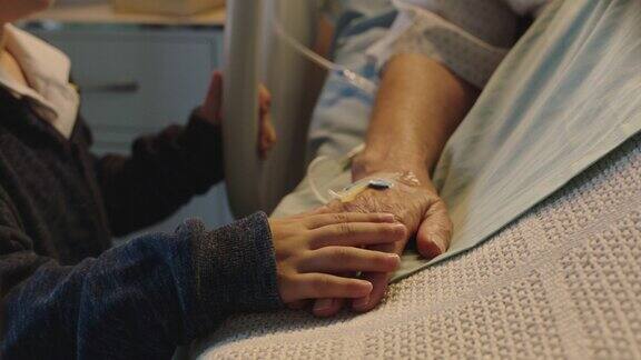 小男孩抚摸着躺在病床上的奶奶的手孩子在病床前对病愈的奶奶表达爱意