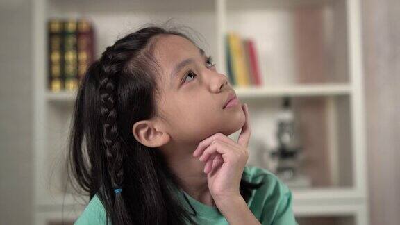 梦幻微笑的亚洲小女孩孩子们坐在一边思考一边在线学习