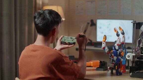 亚洲男孩的背影与3D打印持有和固定板同时修复半机械人的手在家里