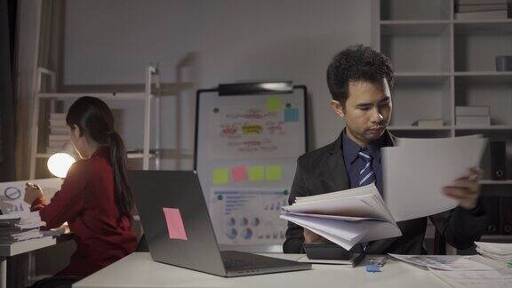 年轻的亚洲商人在办公室里用笔记本电脑和财务文件工作的男人和女人