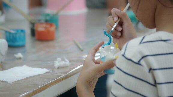 近距离看亚洲小女孩正兴致勃勃地在陶瓷小象上画油画孩子们在学校的艺术和手工艺创意活动班