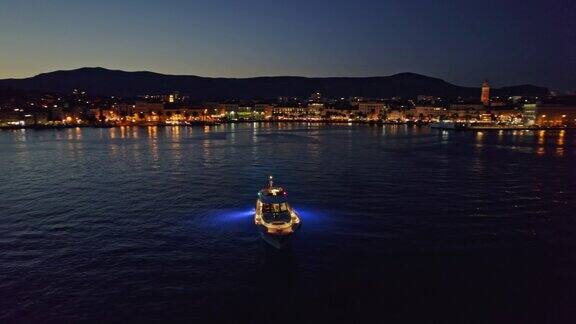 航拍:夜晚停泊在沿海城市海湾中的现代游艇