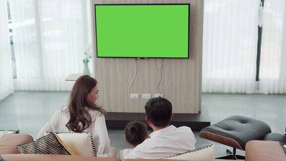 亚洲幸福家庭坐在家里的客厅看电视一起度过宝贵的时间频道到绿色屏幕显示器为您的信息