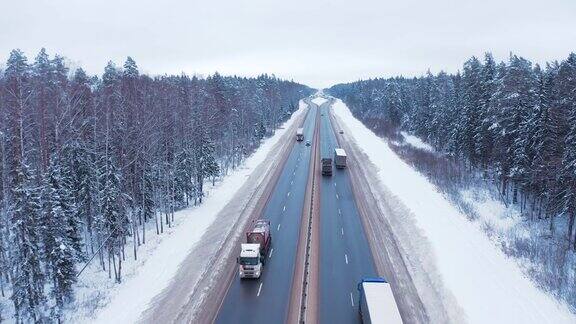 一辆黑色轿车和一辆卡车行驶在白雪覆盖的森林中央的道路上