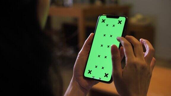 特写女人的手使用智能手机与绿色屏幕