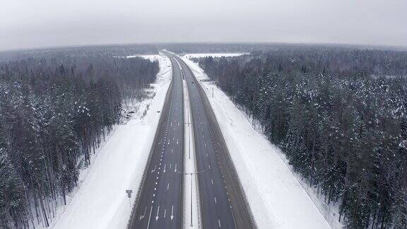 冬天白雪覆盖的森林中间的高速公路上一辆路过的黑色汽车
