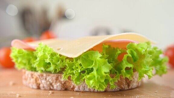 慢镜头中一片奶酪掉在三明治和火腿上