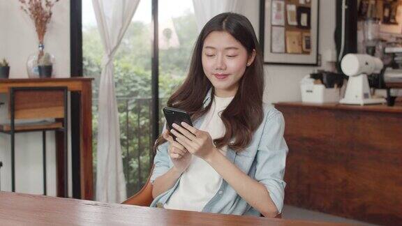 年轻的日本亚洲女孩在咖啡店的桌子上用智能手机上网