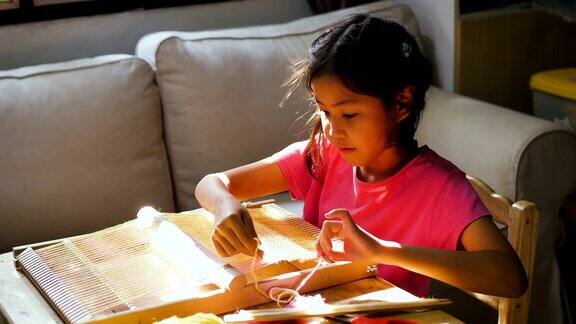 小女孩用织布机在家里自制的木架上织毛线