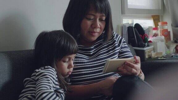 亚洲母女在沙发上玩智能手机