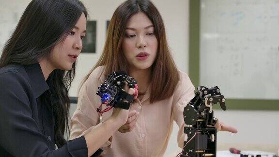 在实验室测试创新机器人技术的工程师团队两位亚洲女性为机械机械手创造运动有技术或创新观念的人