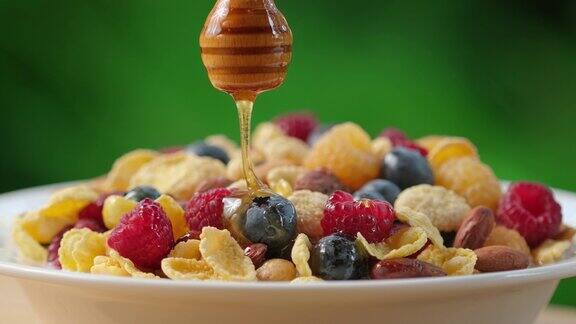 蜂蜜从蜜罐中倒入燕麦粥中在格兰诺拉麦片中加入天然蜂蜜和新鲜浆果