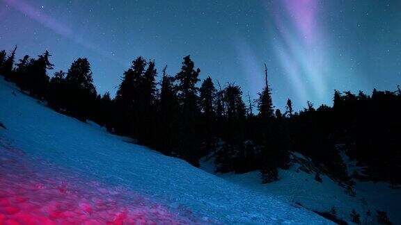 山林红色照明环雪坡上的极光