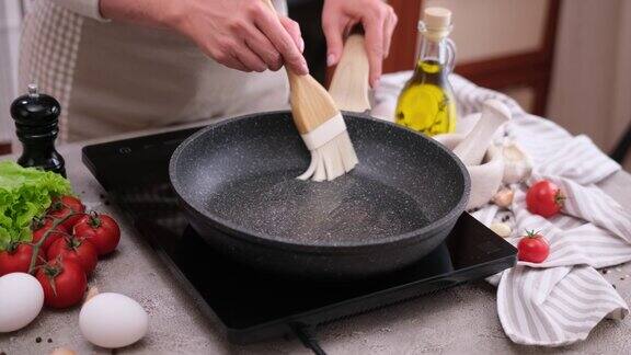 用硅胶刷在热煎锅上抹黄油的女人