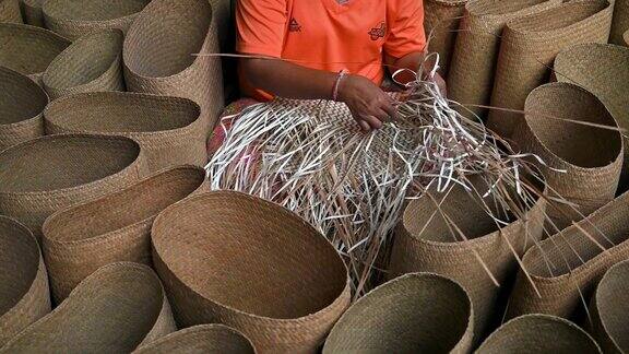 特写的妇女编织一个干叶编织篮子篮子的手工工艺生产