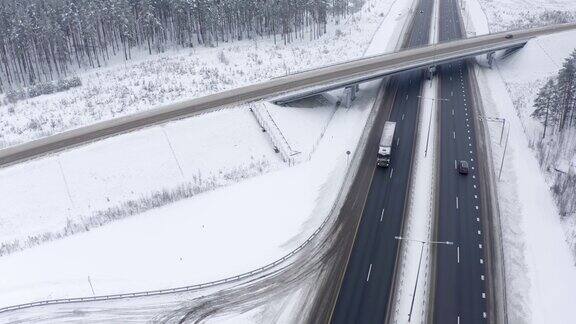 在一个寒冷的冬天两辆卡车行驶在桥下的高速公路上经过一片覆盖着雪的森林