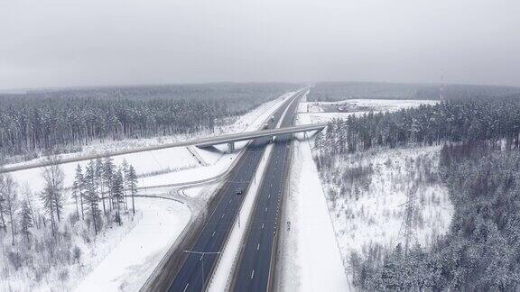 无人机在冬天的道路上与一辆过往的汽车一起飞行前视图