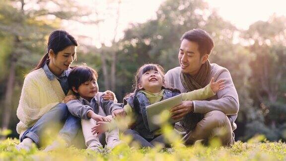 年轻的亚洲家庭在公园草地上放松
