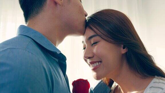 亚洲青年惊喜送玫瑰给美丽的女友迷人浪漫的新婚男女花时间在房子里一起庆祝周年纪念日和情人节