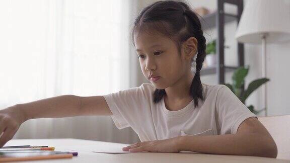 可爱的亚洲女孩在纸上画画在家里享受色彩孩子在家上学