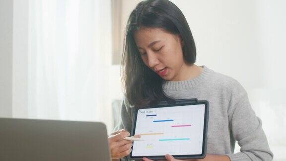 亚洲女商人使用笔记本电脑和平板电脑向同事介绍计划同时在家工作在卧室