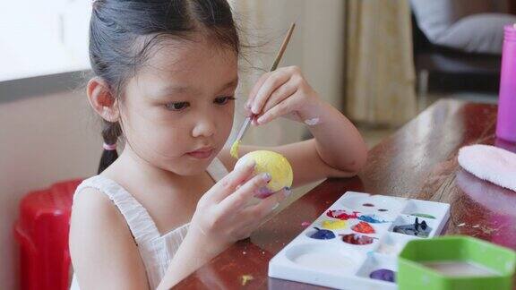一个亚洲女孩和她的家人在给鸡蛋着色孩子和家人准备复活节画和装饰蛋