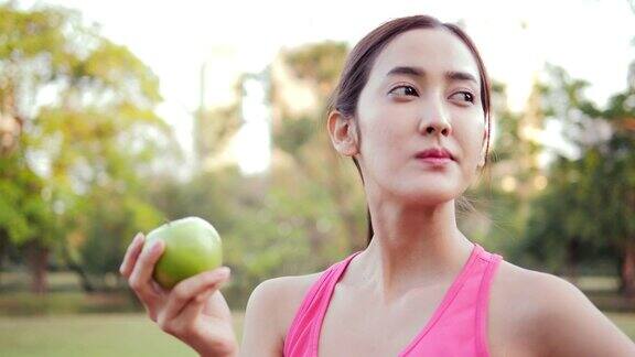 运动亚洲女人在公园吃青苹果有保健理念的女性