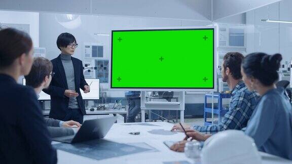现代工业工厂会议:自信的亚洲工程师使用交互式绿色模拟屏幕白板向一组工程师经理做报告