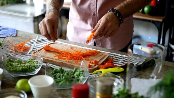 男子用削皮器将胡萝卜切成细长的条状
