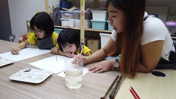 一位亚洲华裔女艺术教师在她的艺术课上教2名中国女青年学生水彩画和着色