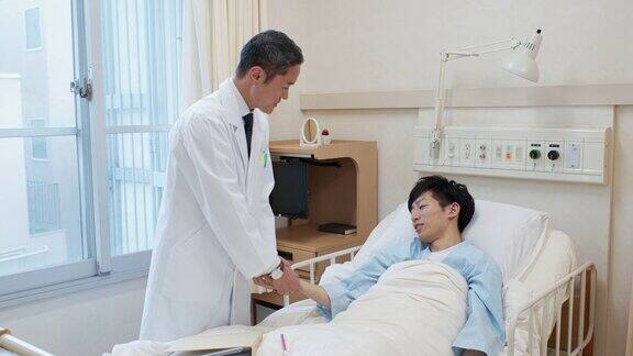 日本病人在病床上与病人交谈并给病人测脉搏