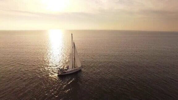 无人机拍摄的日落时分海上的一艘帆船