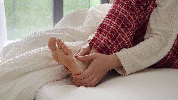 一个女人躺在床上因为肌肉痉挛而感到疼痛她按摩并抱着自己的脚伤害健康问题疼痛和创伤