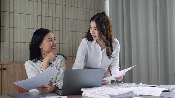 两个商务女性坐在办公桌前讨论项目细节不同的女同事在办公室会面分享意见共同完成任务销售经理向公司客户提出商业报价