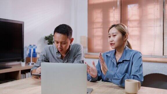 男性企业主一边用电子平板电脑和笔记本电脑写字一边向年轻的亚洲女性财务顾问咨询