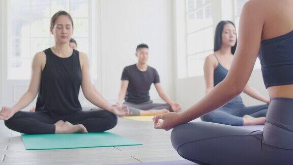一组亚洲人练习瑜伽课与教练在Sukhasana练习禅宗一样