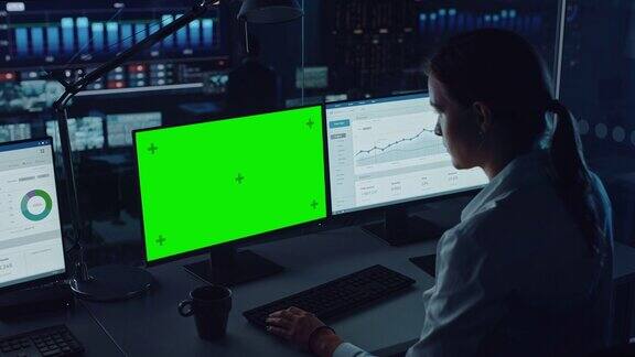 专业金融数据分析师在现代监控办公室的绿屏电脑上工作并在大数字屏幕上实时分析有财务专家的监控室