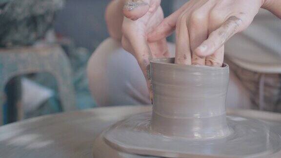 近距离的亚洲妇女粘土艺术家在她的工作室与纺纱陶轮工作