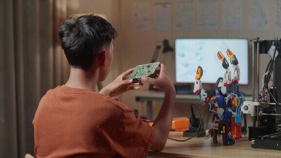 亚洲男孩的背影与3D打印握着和看着板而修复半机械人的手在家里