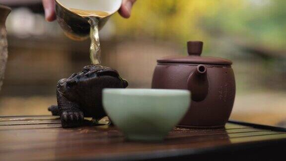 特写镜头茶道大师用碗里的沸水冲洗茶道上的青蛙茶宠