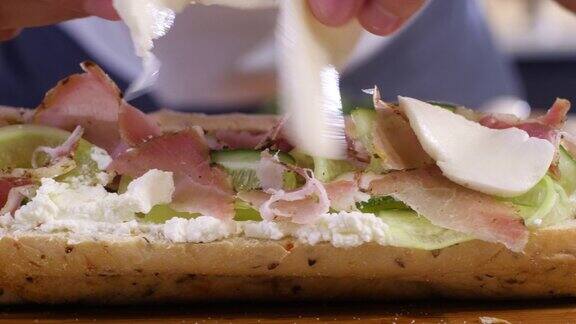 厨师在厨房里把马苏里拉奶酪薄片放在三明治上